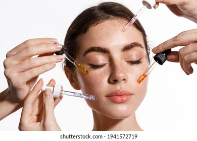 Skin care and rejuvenation. Beautiful Model With Radiant And Glowing Facial Skin Looking At Camera. Moisturizing With Serum Collagen And Hyaluronic Acid. Hands with serum dropper near girl face.