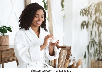 Skin Care Routine. Beautiful Black Girl After Showering Applying Moisturising Cream On Face, Holding Jar With Hydrating Lotion, Free Space - Powered by Shutterstock