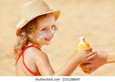 Skin Care. Safe Protection From The Sun. Sunscreen For Children. The Child Holds A Bottle Of Moisturizing Sunscreen In His Hands. Child With A Protective Layer Of Suscreen On His Face.