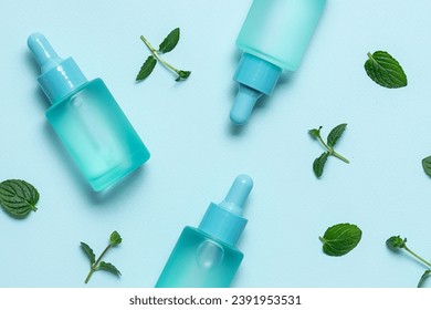 Skin care serum or essential oil in glass blue bottle with dropper on light blue background with fresh green mint leaves top view. Natural herbal cosmetic concept. - Powered by Shutterstock