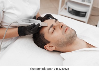 Skin care of ultrasound facial peeling. Ultrasonic cleansing procedure. Crop of beauty treatment of man. Beauty skin care cosmetology in spa salon. 