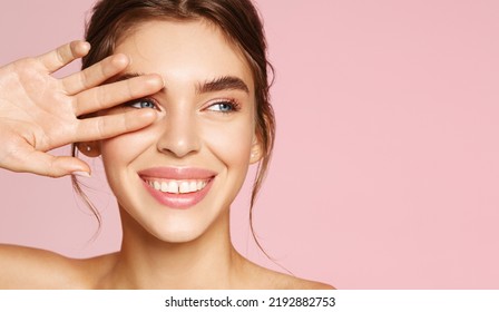 Skin care. Woman with beauty face touching healthy facial skin portrait. Beautiful smiling girl model with natural makeup touching glowing hydrated skin on pink background closeup - Powered by Shutterstock