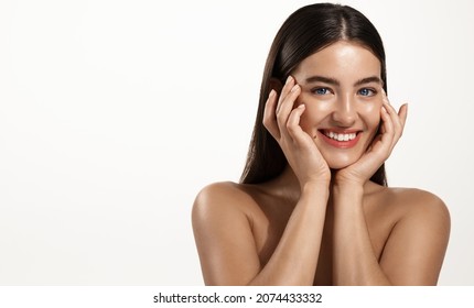 Skin care and women cosmetics. Smiling young woman with clean, glowing facial skin, touching her face after cosmetic product, spa procedure, cleaning face, white background - Shutterstock ID 2074433332