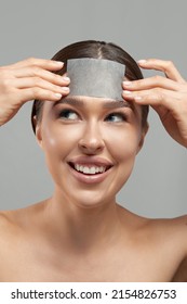 Skin care. Young woman removing oil from face using blotting papers. Beautiful girl model with smooth and healthy skin