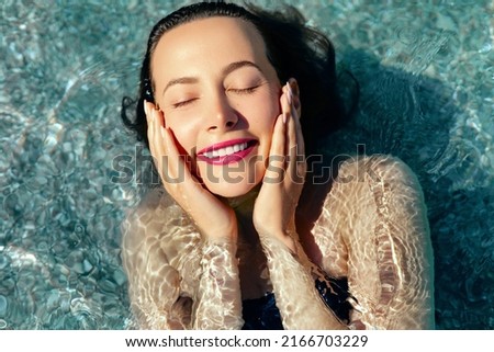 Skin hydration. Young beautiful  female model with make up and perfect skin swimming in the transparent sear or pool. Natural skin care concept