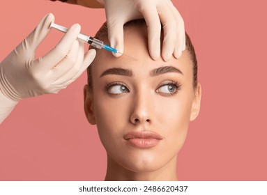 Skin Lifting Injection. Young Woman Receiving Botox Beauty Injection In Forehead Standing Over Pink Background. Studio Shot - Powered by Shutterstock