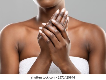 Skin nutrition concept. Unrecognizable african american woman applying moisturizing cream to her hands over gray studio background, crop