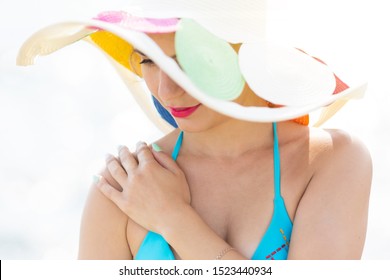 The skin on the woman’s shoulder burned in the sun, pain from a burn. The girl covers her tanned shoulder with her hand.