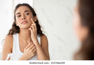 Skin Problem. Depressed Woman Touching Pimple On Face Looking At Mirror In Modern Bathroom. Facial Skin Issues, Medical Care And Treatment Concept. Selective Focus - Shutterstock ID 2157666109