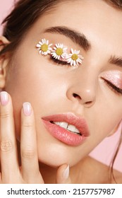 Skin rejuvenation and beauty. Closeup of perfect woman face with chamomile on eyelid, eyes closed. Abstract of facial natural moisturizer, eye patches with active botanical effects