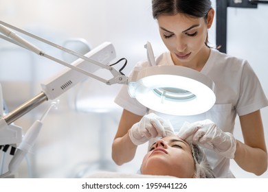 Skin treatment, beautician squeezing pimples from face of young female. Cleansing facial skin, beautician squeezed blackheads. - Shutterstock ID 1959441226