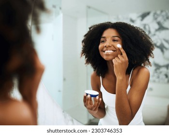 Skincare, bathroom mirror and black woman with cream, smile and morning dermatology routine. Health, wellness and luxury skin care at home, girl in reflection with lotion on face for facial treatment - Powered by Shutterstock