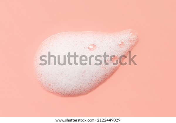 Skincare cleanser foam texture. Soap, shampoo,\
cleansing mousse bubbles swatch on pink color background. Face wash\
lather closeup