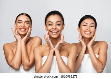 Skincare Concept. Three Diverse Women Touching Face Caring For Perfect Skin Standing On Gray Background, Smiling To Camera