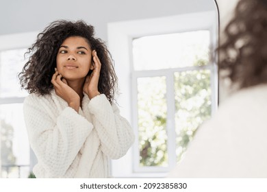 Skincare, Dermatology And Cosmetology Concept. Young African American Woman Standing At Bathroom, Looking At Mirror. Female In Bathrobe Checking Skin, Touching Her Perfect Face And Smiling Nice