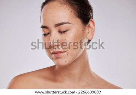 Skincare, face and beauty of a woman in studio for cosmetic, dermatology and makeup shine. Aesthetic asian model person with wellness glow, mole on skin and luxury facial self care on grey background