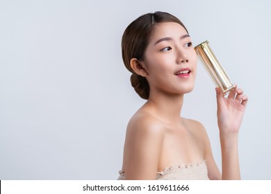 Skincare And Makeup Concept Beautiful Asian Female Woman With Healthy Facial Skin Close Up Portrait Studio Shot Hand Hold Serum Pr Cream Package With Happiness And Joyful