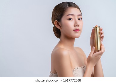 Skincare And Makeup Concept Beautiful Asian Female Woman With Healthy Facial Skin Close Up Portrait Studio Shot Hand Hold Serum Pr Cream Package With Happiness And Joyful