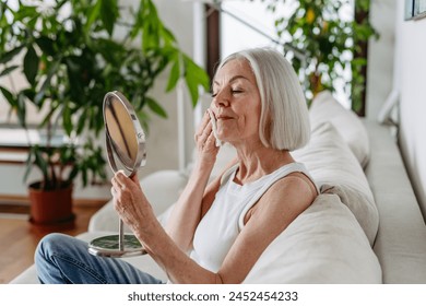 Skincare for mature woman. Portrait of beautiful older woman with gray hair cleaning, taking care of her skin. - Powered by Shutterstock