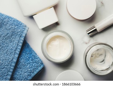 Skincare Products.Cream Jars,lotion, Exfoliating Cream And A Blue Towel On A Marble