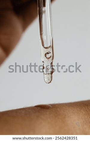 skincare routine, a drop of serum, Squeezing the cosmetic product onto hands, a drop of face oil falls on the hand, oil pouring out of a pipette

