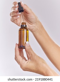 Skincare Serum, Essential Oil And Cosmetic Product In Woman Hand For Perfect, Smooth Skin Or Reduce Wrinkles Isolated On Studio Background. Closeup Hands Using Body Care Or Anti Aging Liquid Drop