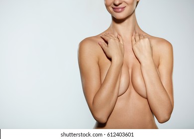 Skincare. Smiling Naked Young Woman Covering Perfect Tight Breast Posing On Grey Background. Closeup Of Female Hot Sexy Body And Hands On Chest. Beauty Concept. High Resolution