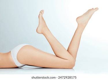 Skincare, underwear and woman legs on floor for wellness with waxing or epilation and beauty in studio. Bikini body, model girl and thigh for hair removal cosmetics and grooming by white background