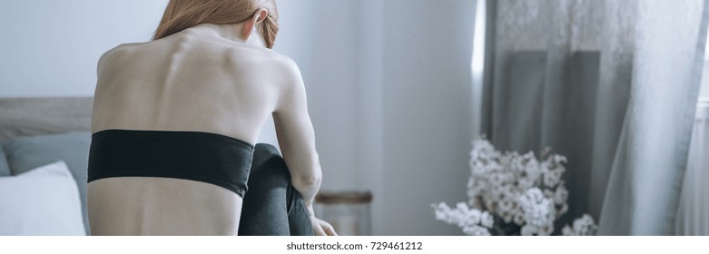 Skinny Back Of Bulimic Woman Sitting Depressed And Alone In Eating Disorder Treatment Center