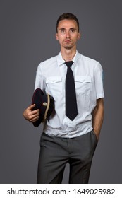 Skinny Russian Man In Police Office Uniform And Cap Looking At Camera With Serious Face Against Gray Background