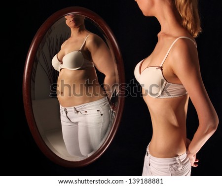 Skinny woman seeing herself fat in a mirror Imagine de stoc © 