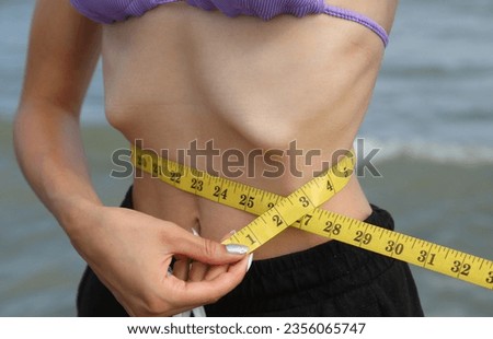 skinny young girl with eating disorder measuring ther waistline Imagine de stoc © 