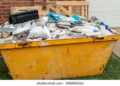 Skip Bin Container Full Of Household Waste Rubbish On The Front Yard. House Clean Up And Renovation Concept.