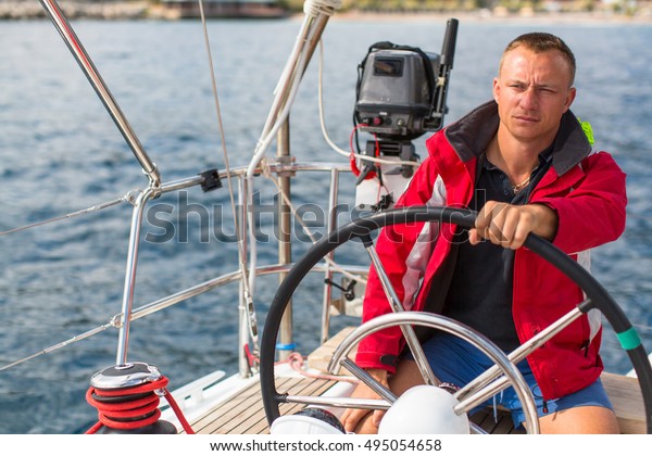 Skipper at the\
helm controls of a sailing\
yacht.