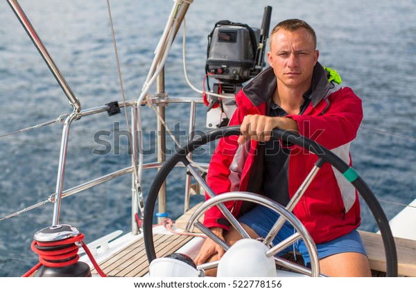 Skipper at the helm controls of a sailing yacht.\
Lifestyle, sport and\
leisure.