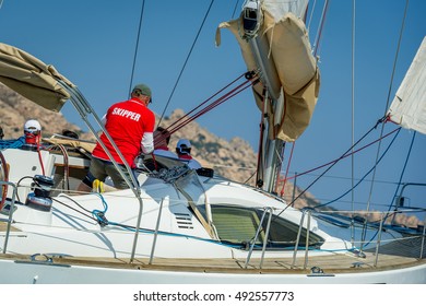Skipper in red t-short is working with a winch of his sailing boat. Sailing regatta in the Mediterranean sea.