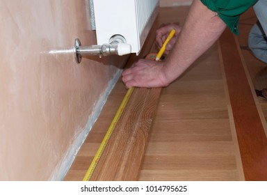 Skirting Board & Architrave. Repairman's hands Installing Skirting Board Oak Wooden Floor. Measuring tape, Hardwood Flooring and Repair.
