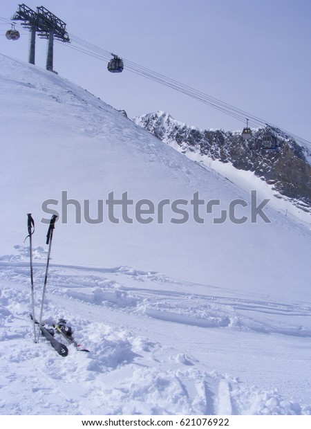 Skis and poles sticking out of the snow with cable cars\
in the b