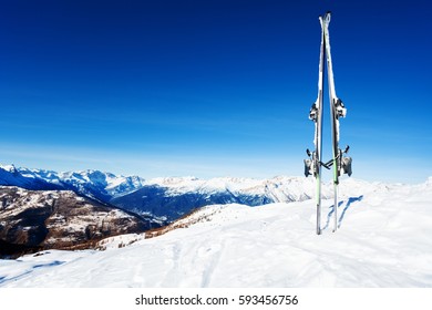 Skis Stuck In Snow Bank Against Mountain Scene