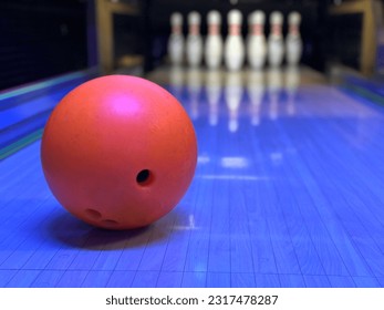 Skittles and bowling ball, blurred background. Red ball on the background of skittles. Game club, bowling set.