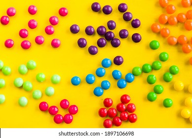 Skittles candy on the yellow table, colorful sweet candy background, high angle view