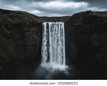 Skogafoss waterfall cascades from a rocky cliff under an overcast sky, captured by drone in Iceland - Powered by Shutterstock