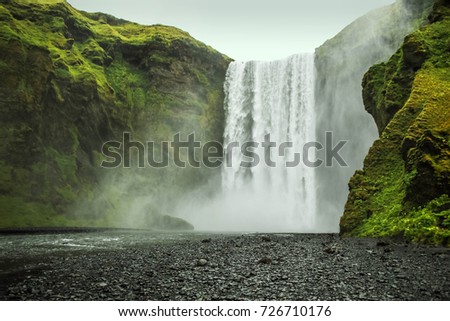 Skogafoss waterfall falling down from green hills, Iceland