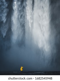 Skogafoss Waterfall In Iceland. Man In Yellow Jacket