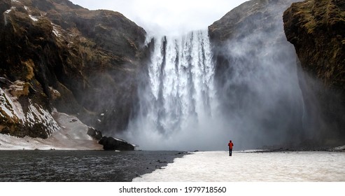 Skogafoss Waterfall With Solitary Person Standing Near To The Flow. Winter Scene In Southern Iceland. 