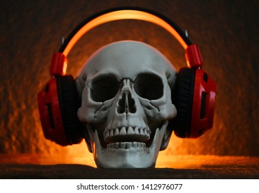 Skull music with headphone / Human skull listening to music earphone decorated at halloween party and light on dark background 