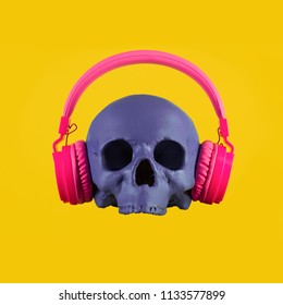Skull in pink headphones on a yellow background. Fashion minimal art.