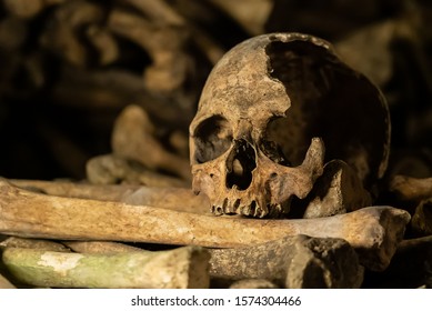 Skulls and bones in catacombs. Old broken skull placed on the bones. Underground cemetery.