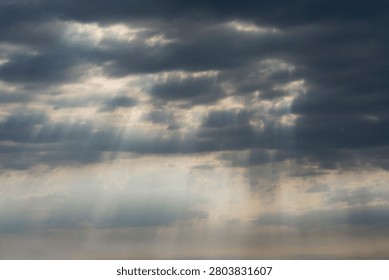 Sky Background. Detail view of a cloudscape with sun's rays piercing through storm clouds