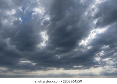 Sky Background. Detail view of a cloudscape with sun's rays piercing through storm clouds